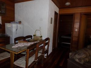 comedor con mesa, sillas y nevera en Recanto na Montanha de Gramado, en Gramado