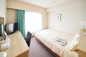 Habitación de hotel con cama, escritorio y ventana en AkishimaStationHotel TOKYO, en Akishima
