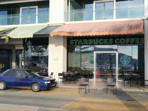 a blue car parked in front of a starbucks coffee shop at 5 Bedrooms Penthouse 3 Bedrooms Apartment Marina Court Resort Condominium in Kota Kinabalu