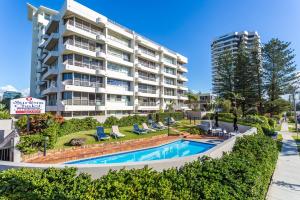 un grand immeuble avec piscine et chaises longues dans l'établissement Surfers Chalet, à Gold Coast