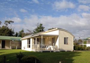 a small white house with a porch on a lawn at Beauty Point Tourist Park in Beauty Point