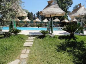 un resort con piscina con ombrelloni e piscina di Le Camporelle In Campagna a Cavallino di Lecce
