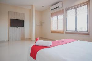a bedroom with a white bed and a tv at RedDoorz Plus near Ferry Terminal Batam Center in Batam Center
