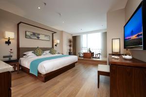 揚州市にあるSSAW Boutique Hotel Yangzhouの大きなベッドと薄型テレビのある寝室