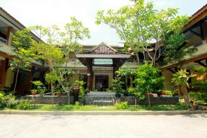 a building with a gate and trees in front of it at The Soemarsono Hotel in Yogyakarta