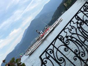 een grote boot op het water met bergen op de achtergrond bij Hotel Concordia in Porlezza
