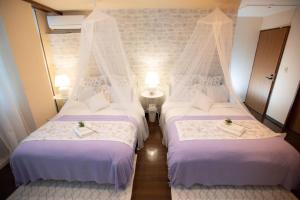 two beds in a hotel room with white sheets at White House in Uruma