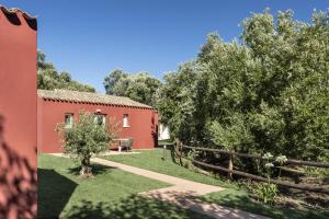 a red house with a fence and trees at Li Neuli Country Club in San Pantaleo
