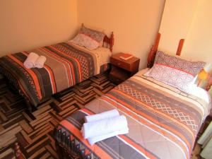 2 camas en una habitación pequeña con toallas y zapatos en Full Suites, en Cusco