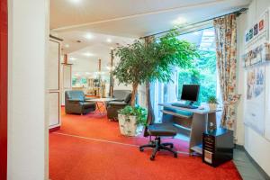 ein Büro mit einem Schreibtisch und einem Computer auf einem roten Teppich in der Unterkunft Quality Hotel Hof in Hof