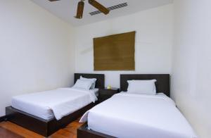 Habitación con 2 camas, paredes blancas y suelo de madera. en Sabah Beach Villas & Suites, en Kota Kinabalu