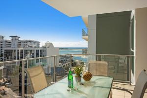a glass table and chairs on a balcony with a view of the ocean at m1 Resort in Maroochydore