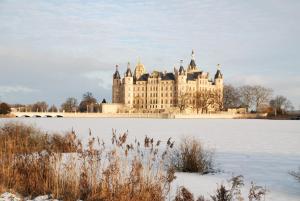 een groot kasteel bovenop een met sneeuw bedekt veld bij Hotel Elefant in Schwerin