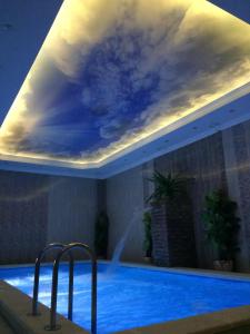 a swimming pool with a cloud painting on the ceiling at Hotel Usadba in Georgiyevsk