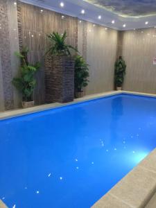 a large blue swimming pool with potted plants at Hotel Usadba in Georgiyevsk