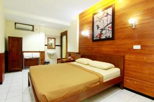 1 dormitorio con 1 cama con pared de madera en The Soemarsono Hotel, en Yogyakarta