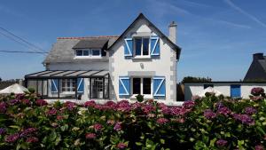 une maison blanche avec des fenêtres bleues et des fleurs violettes dans l'établissement Maison de bord de mer à Keriec, à Trélévern