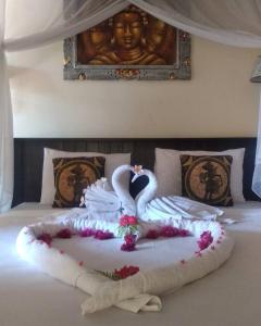 a bed with a swan made out of flowers at Ode Resto Guesthouse in Pemuteran