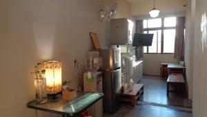 a kitchen with a refrigerator and a table with a lamp at Temple Side Hostel in Tainan