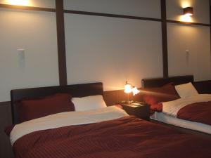 a bedroom with two beds and a lamp on a table at Shinseikan in Nishiwaga