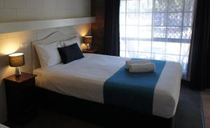 1 dormitorio con 1 cama blanca grande con manta azul en Cleveland Motor Inn, en Cleveland
