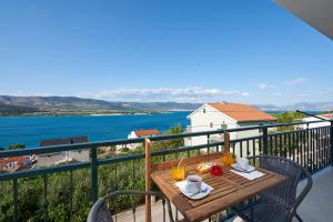 a table on a balcony with a view of the water at Apartment Ugrina in Trogir