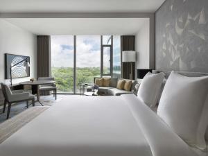 バンガロールにあるFour Seasons Hotel Bengaluru at Embassy ONEのベッドルーム(大きな白いベッド1台付)、リビングルームが備わります。