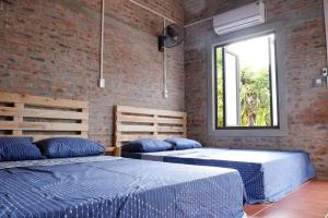 two beds in a room with a window at Datani Mộc Châu Homestay in Làng Môn