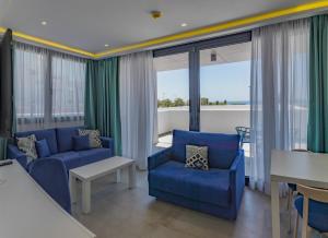 a living room with blue furniture and large windows at Hotel Playa de la Plata in Zahara de los Atunes