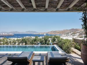 a swimming pool with chairs and a view of the ocean at Belvedere Mykonos - Hilltop Rooms & Suites - The Leading Hotels of the World in Mýkonos City