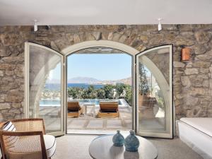 a living room with a large glass door leading to a patio at Belvedere Mykonos - Hilltop Rooms & Suites - The Leading Hotels of the World in Mýkonos City
