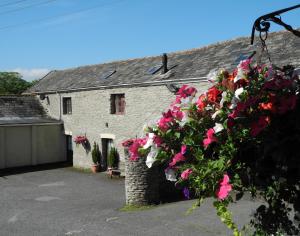 a house with a bunch of flowers hanging from it at Trimstone Manor Country House Cottages in West Down