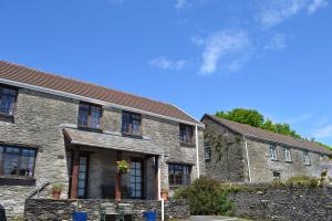 an old stone house with a fence in front of it at Trimstone Manor Country House Cottages in Ilfracombe