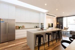 una cucina con armadi bianchi e un'isola con sgabelli da bar di Lola Three Levels of Style with Rooftop Terrace a Melbourne