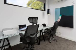 oficina con 2 sillas y escritorio con ordenador portátil en Lola Three Levels of Style with Rooftop Terrace, en Melbourne