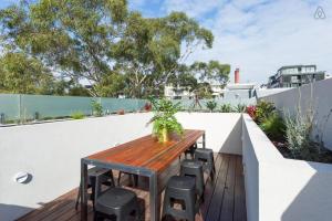 una mesa de madera en un balcón con taburetes en Lola Three Levels of Style with Rooftop Terrace, en Melbourne