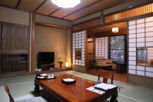 a living room with a wooden table and a television at Ryokan Wakaba in Minamioguni