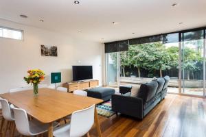 a living room with a table and a couch and a television at Bradman Modern Style a Walk to MCG, Swan St, CBD in Melbourne