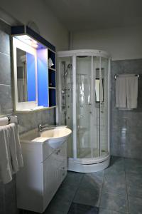 biała łazienka z prysznicem i umywalką w obiekcie Pension Varadia w mieście Oradea