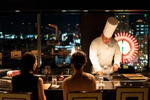 a chef preparing food on a counter in a restaurant at Kobe Meriken Park Oriental Hotel in Kobe