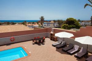 un patio con mesas y sillas y una piscina en Vv ORAMAS, en Caleta de Fuste