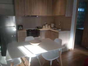 a kitchen with a white table and white chairs at The Little Gem Under The Rocks in Kastraki