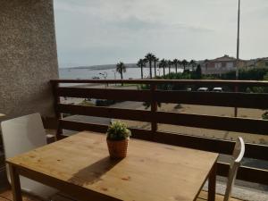 una mesa de madera con una maceta en un balcón con playa en Appartement neuf 6 couchages 50 metres de la plage, en Gruissan