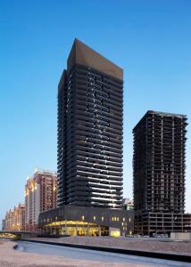 a tall building in front of two tall buildings at SHH -Furnished Studio Apartment in Matrix Tower, Sports City in Dubai