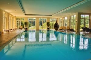 a large swimming pool in a room with windows at Parkhotel Surenburg in Hörstel