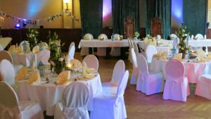 un grupo de mesas con sillas blancas en una habitación en Hotel Elefant, en Schwerin