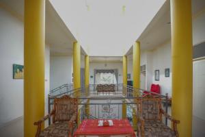 a hallway with yellow columns and a table and chairs at RedDoorz Syariah near Museum Lambung Mangkurat 2 in Banjarbaru