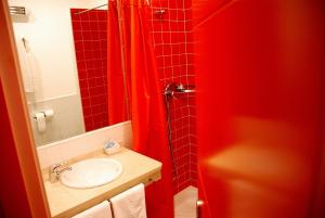 a bathroom with a sink and a red shower curtain at Hostal El Cardenillo in Madrigal de la Vera