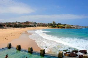 a beach with a person standing in the water at Stylish and Spacious Beach Apartment in Sydney