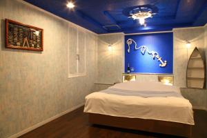 1 dormitorio con 1 cama grande y pared azul en Santa no Ouchi-LoveHotel, en Miyazaki